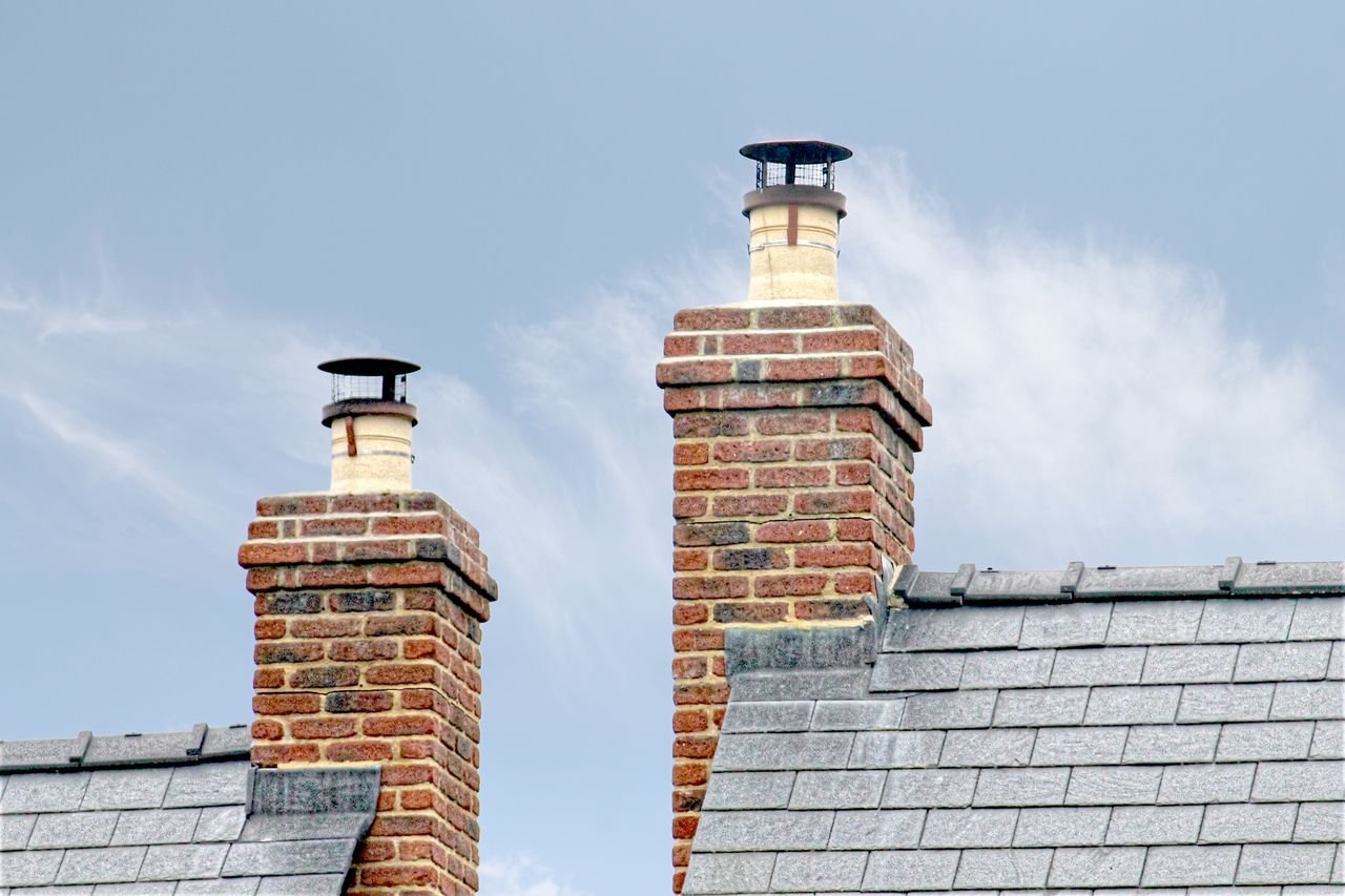 services-01 Close-up of traditional brick chimneys on a slate roof, England.